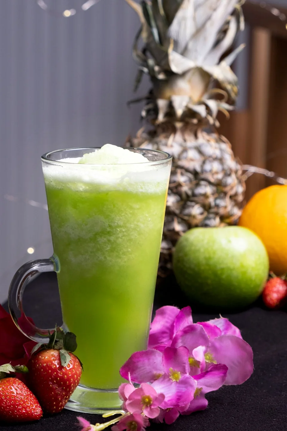 Bright green fruit drink styled with fresh fruit